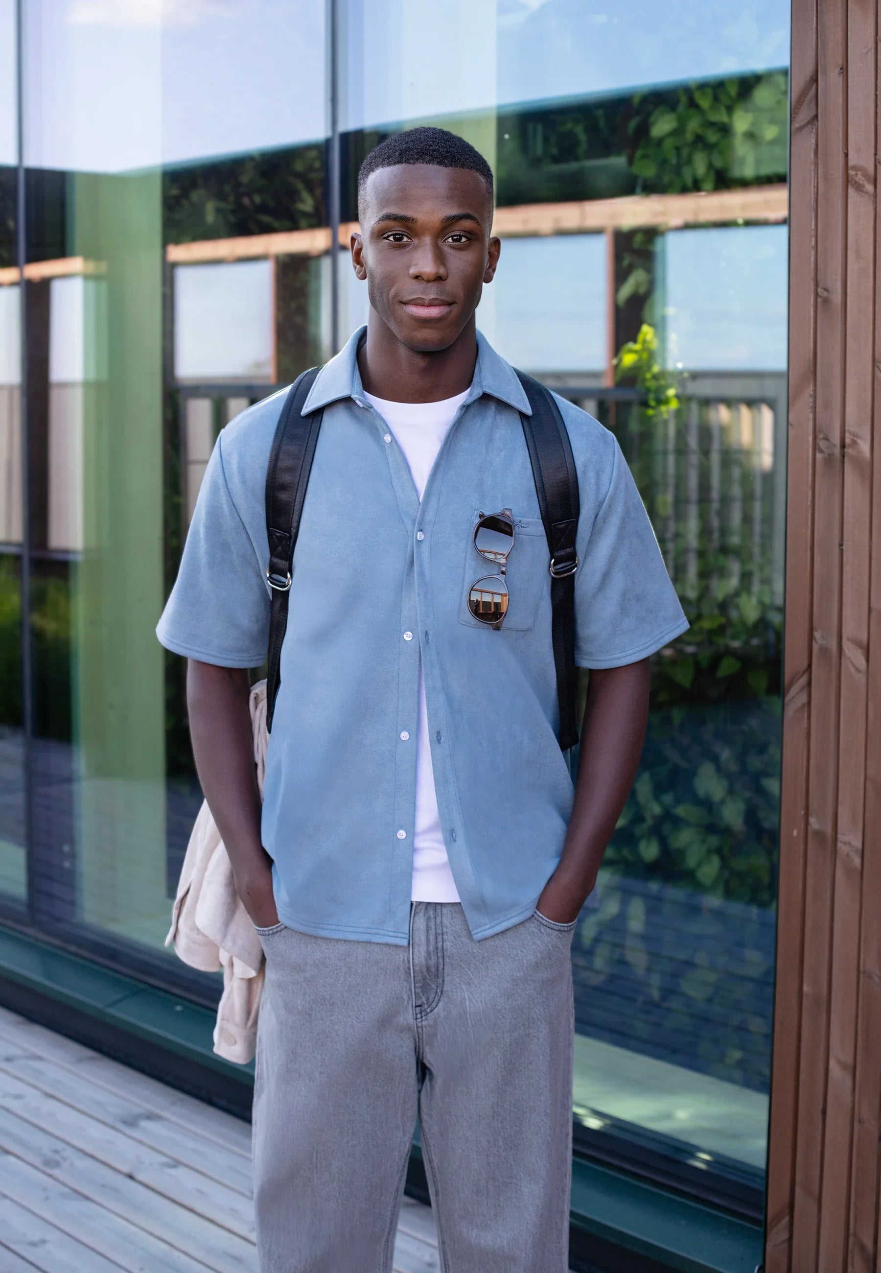 Man in an oversized blue suede short sleeve shirt and grey jeans