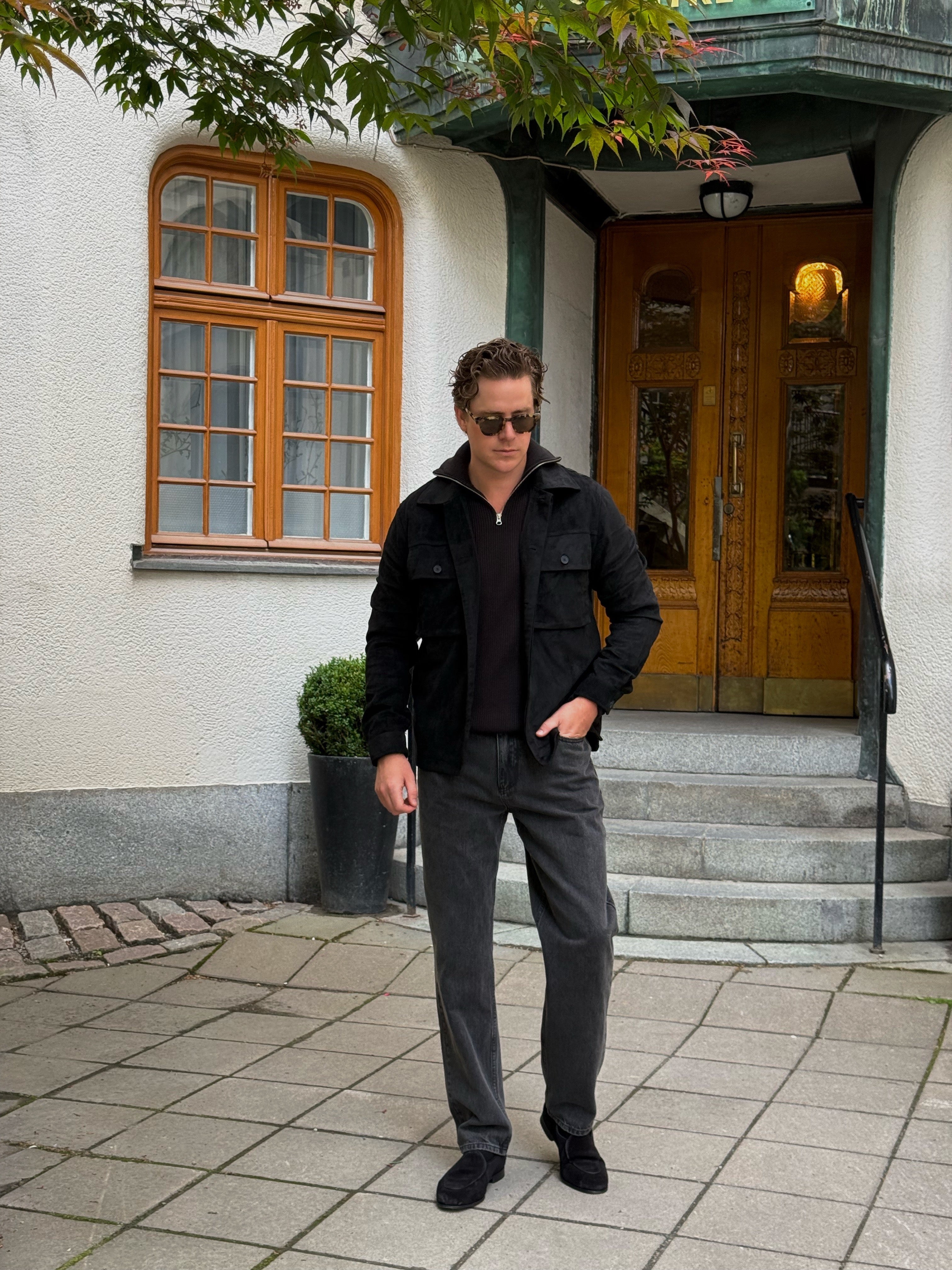 Martin Hansson walking in a black overshirt and tailored grey trousers